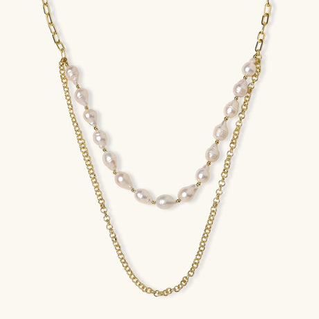 Layered gold chain necklace with organic baroque freshwater pearls and adjustable length on cream background
