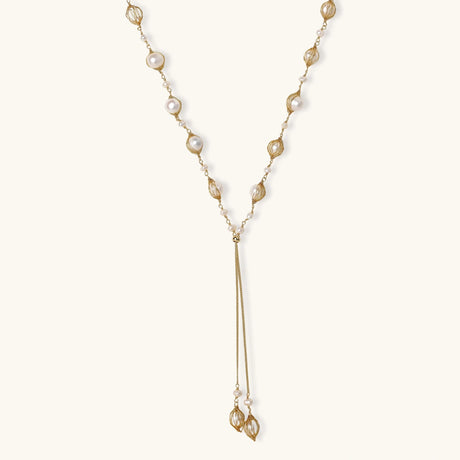 Adjustable gold lariat necklace with freshwater pearls nested in delicate cage settings and Y-shaped tassel drop